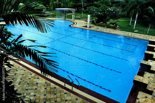 Obraz A serene swimming pool atmosphere, perfect for family vacations, featuring crystal-clear water, adorned with plants and a pavilion for relaxing and enjoying a sunny day