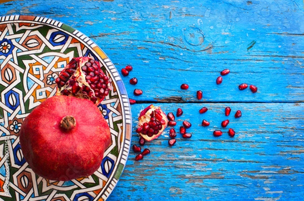 Obraz red ripe pomegranate in dish oriental style with copy space on wooden background