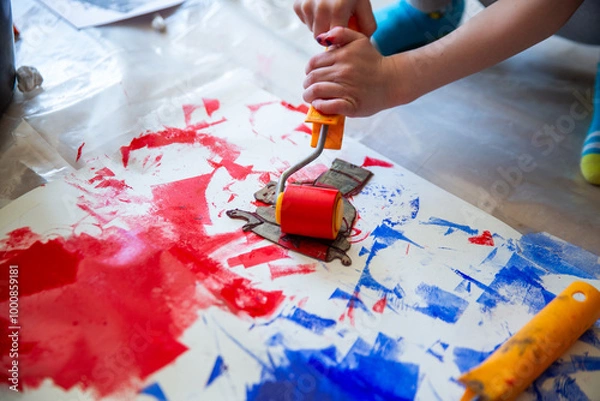 Fototapeta Children creating lino cut prints on paper using rollers, paint, and spoons in an art workshop. Creativity, craft techniques, and artistic expression, educational and creative stock imagery.