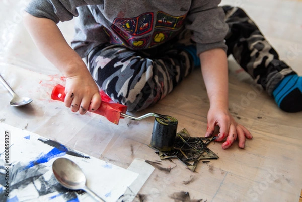 Fototapeta Children creating lino cut prints on paper using rollers, paint, and spoons in an art workshop. Creativity, craft techniques, and artistic expression, educational and creative stock imagery.