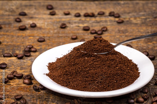 Obraz Ground coffee on white plate with sorrounding coffee beans