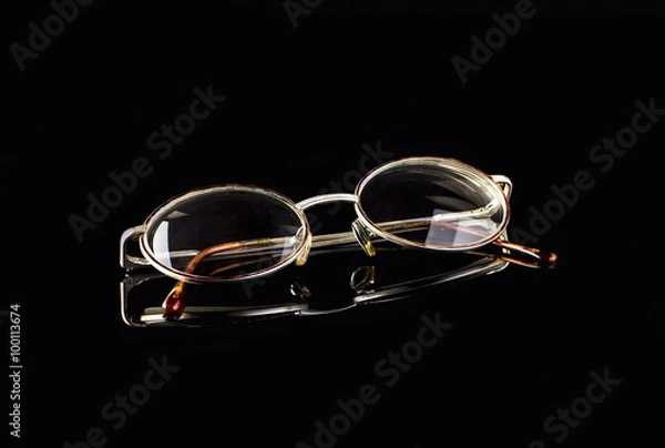 Obraz Retro reading glasses on black mirror background