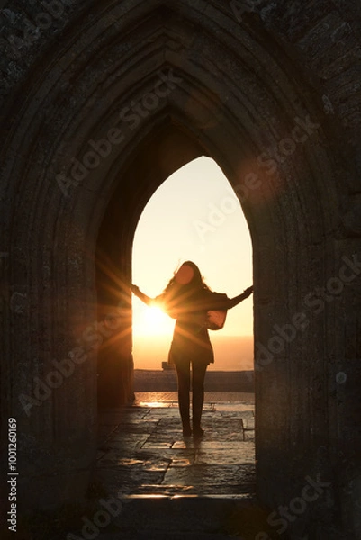 Obraz Silhouette of a woman Framed by an Archway of Glastonbury Tor at sunrise
