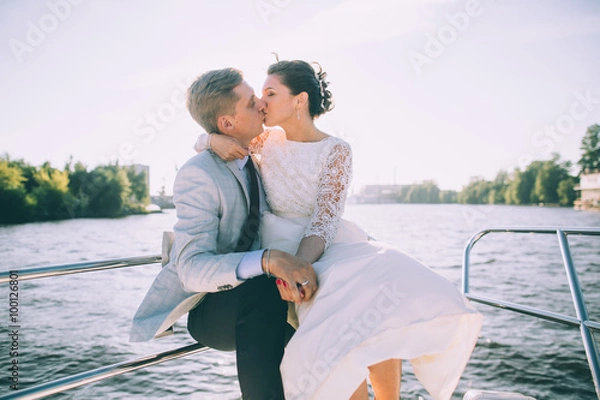 Fototapeta Happy bride and groom on a yacht traveling together on a warm summer day
