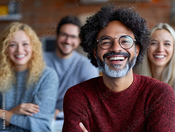 Obraz Diverse group of smiling friends sitting together with focus on joyful man in red sweater and glasses