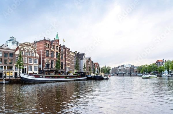 Fototapeta Day view in Amstel, Amsterdam, Netherlands with canal and typical Dutch houses.