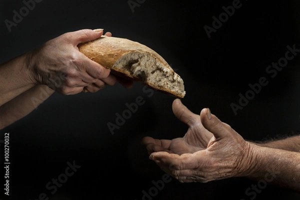 Fototapeta Ręka kobiety podaje bochenek chleba biednemu bezdomnemu. Pojęcie ubóstwa, marginalizacji, głodu na świecie