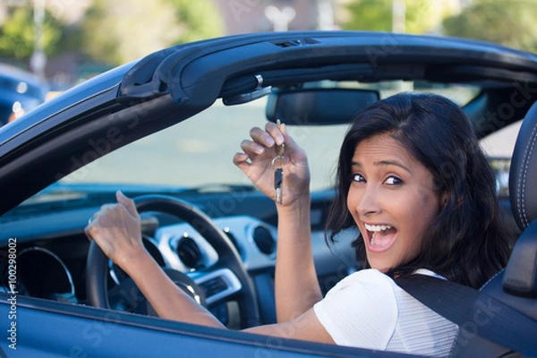 Fototapeta Closeup portrait, young cheerful, joyful, smiling, gorgeous woman holding up keys to her first new sports car. Customer satisfaction