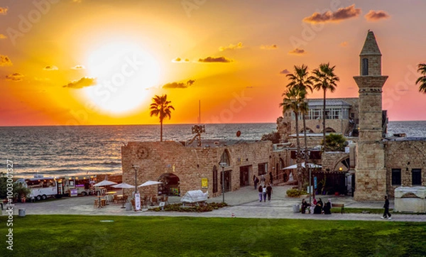 Fototapeta Sunset. View of the old city of Caesarea with the sunset in the sea in the background