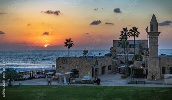 Fototapeta Sunset. View of the old city of Caesarea with the sunset in the sea in the background