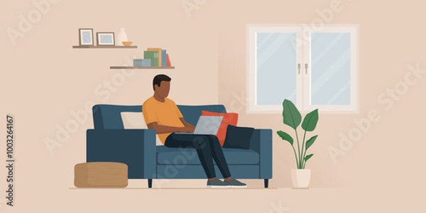 Fototapeta Man sitting on the couch and typing on a laptop