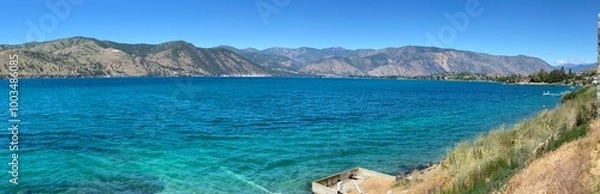 Fototapeta A Lake Chelan panoramic landscape showing the incredible blue of the lake with the contrast of the arid hills in the background and a beautiful early summer day_20240623.