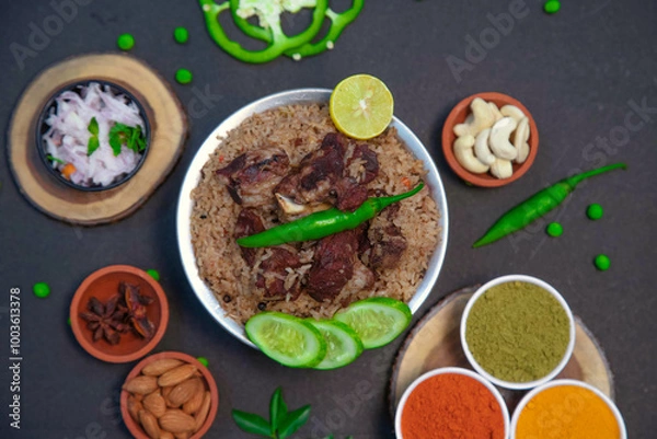 Fototapeta mutton biryani, beef biryani, chicken biryani along with cucumber slice, onion, onion raita, capsicum, cashews, almond, green peas, egg, chili powder, coriander powder and spices on silver bowl
