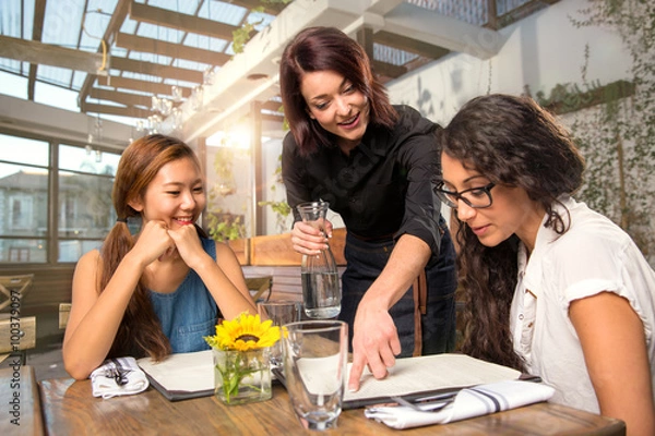 Obraz Kelner na serwerze wskazujący na menu dla klienta, który pomaga przy lunchu przy stole