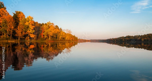 Fototapeta Jezioro w północnym Ontario o zachodzie słońca w późny letni dzień. Lustrzane odbicia i świecący pomarańczowy las.