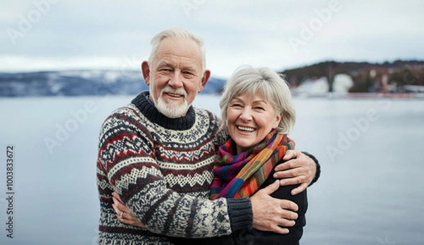Fototapeta Portrait of happy scandinavian senior couple embracing each other in front of the nordic winter sea
