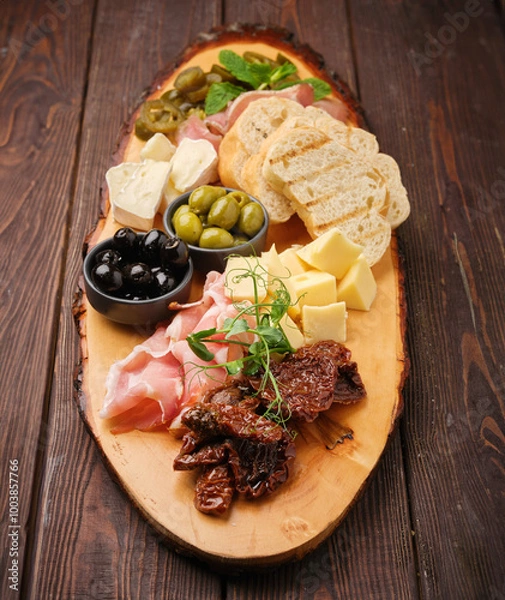 Obraz A vibrant charcuterie board filled with artisanal cheeses, cured meats, olives, and fresh herbs on a rustic wooden platter