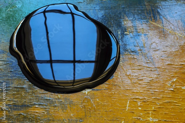 Obraz Oil spill on orange and blue work table with window reflection 