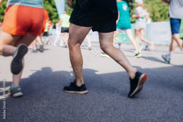 Fototapeta Marathon runners crowd, sportsmen participants start running the half-marathon in the city streets, crowd of sportswomen joggers in motion, group athletes outdoor training competition in a summer day