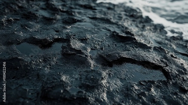 Fototapeta Close-up of dark, textured rock surface with small pools of water reflecting light.