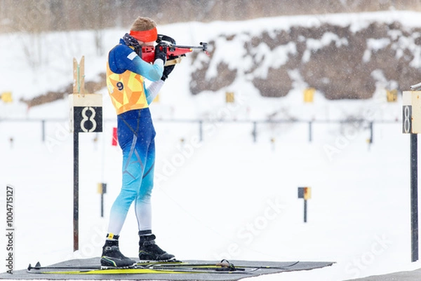 Fototapeta Athlete shooting in standing position at the range in a biathlon competition