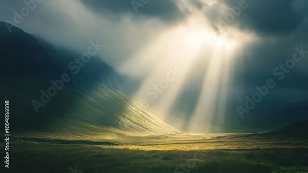 Fototapeta Sunbeams break through the clouds, illuminating a valley.
