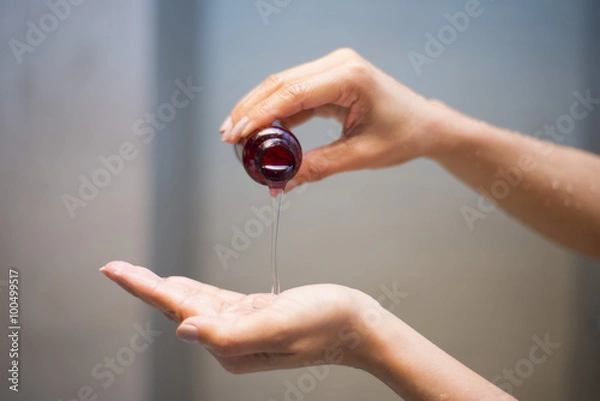Obraz kobieta leje szampon z butelki do ręki