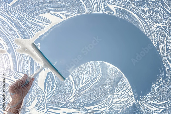 Fototapeta Window cleaner using a squeegee to wash and clean a window