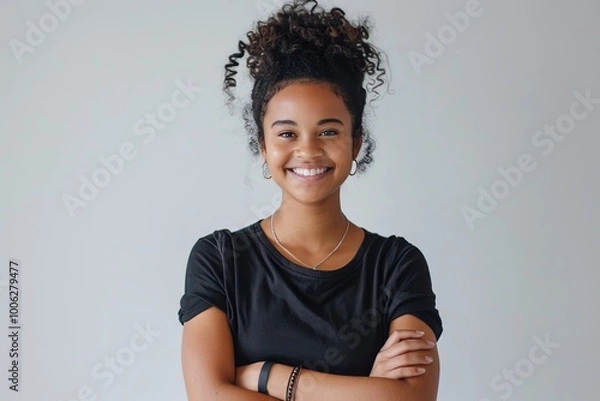 Fototapeta Portrait of a young woman with a genuine smile and arms folded, against a white background , background blur