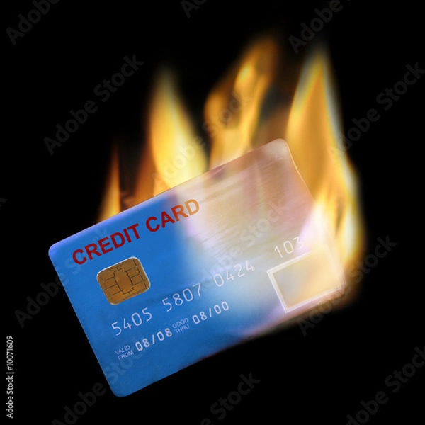 Fototapeta Bank credit card in flames on black background.
