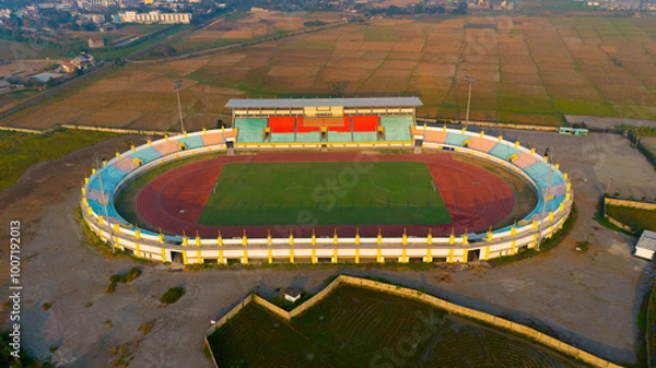 Fototapeta Aerial view of a vibrant sports stadium basking in the warm glow of sunrise, ready for action-packed events
