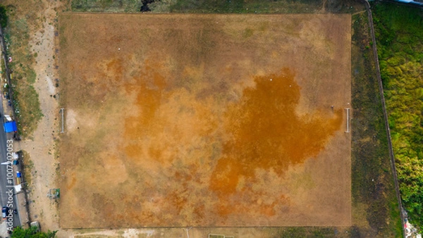 Fototapeta Aerial view of a parched playing field with contrasting textures, illustrating themes of drought and the impact of climate change on local environments