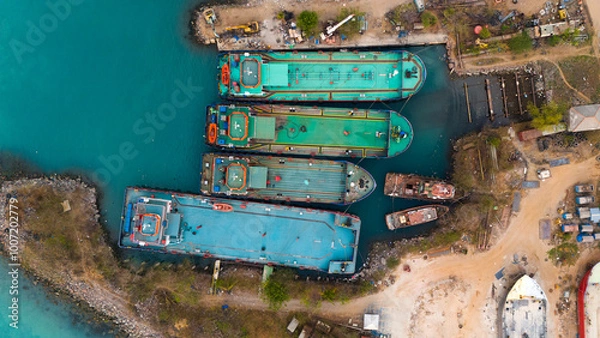 Fototapeta Aerial view of colorful cargo ships docked at a bustling industrial port showcasing the vibrant hustle of maritime logistics
