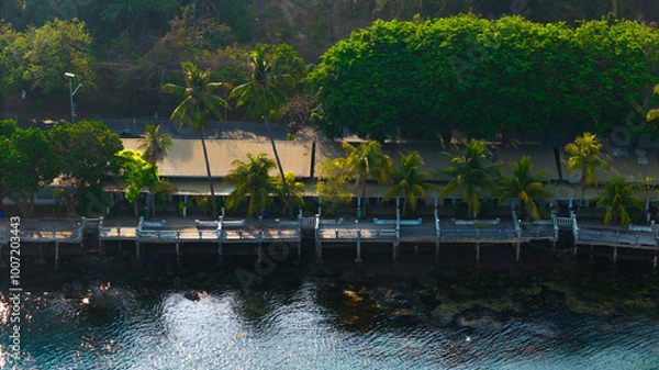 Fototapeta Serene tropical waterfront with lush greenery and tranquil waters inviting peaceful reflection at dusk