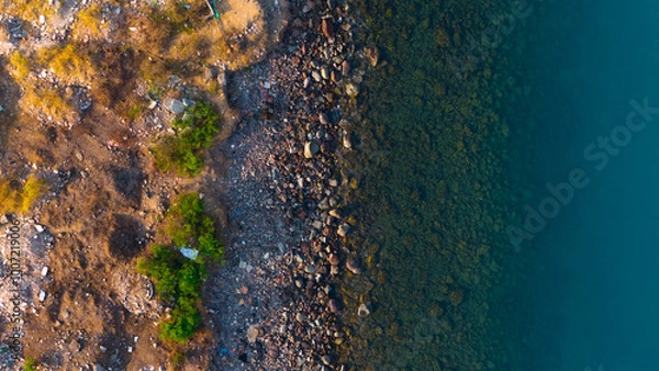 Fototapeta Aerial view of the vibrant interface where land meets water, showcasing nature's captivating textures and colors