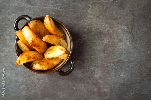 Obraz Bowl of chunky potato wedges fries served on a rustic stone, slate, gray table top.