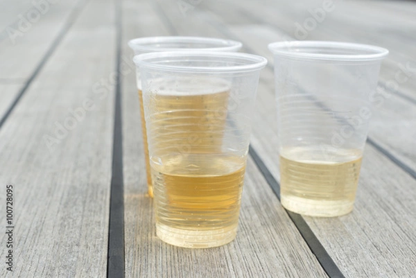 Obraz Champagne in plastic cups on wooden table