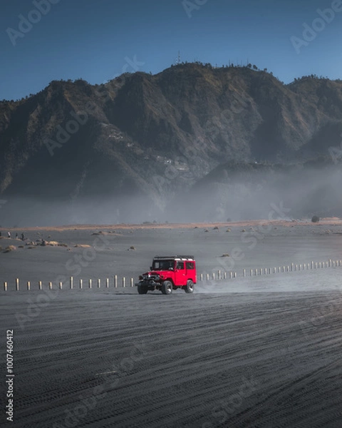 Obraz Wide shot of a red 4x4 in volcanic sand.