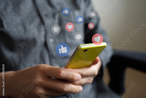 Obraz スマートフォンでSNSアプリを見ている人の手。いいね、お気に入り、コメントのアイコンが表示されている。ソーシャルメディアやコミュニケーションに関する概念的なイメージ。