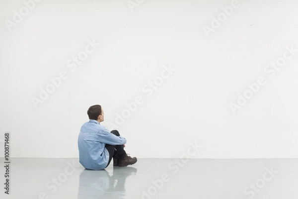 Obraz Man sitting in front of a white wall