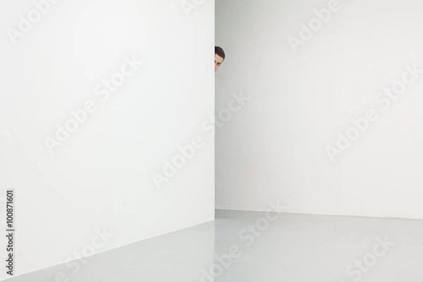 Obraz Man in white room looking from behind corner