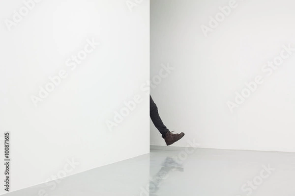 Obraz human leg in white room walking from behind corner