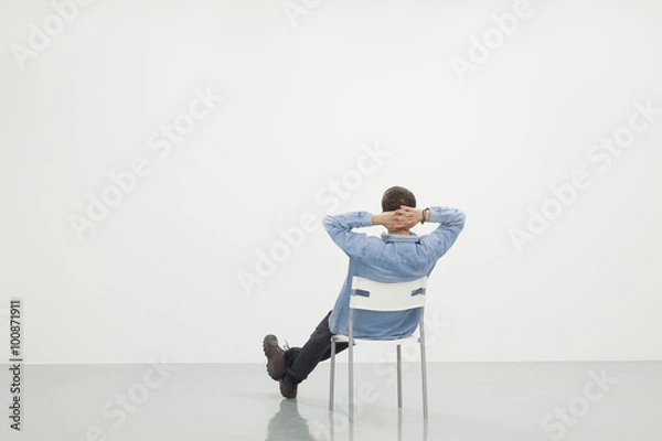 Obraz Man sitting on a chair in white room