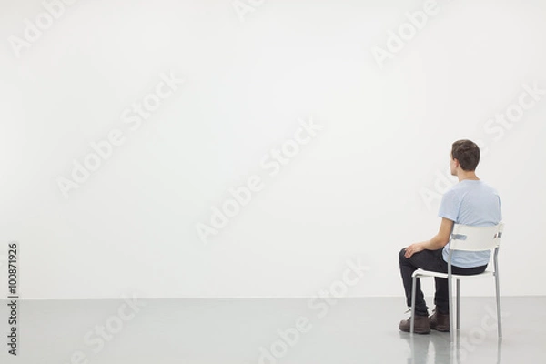Obraz Man sitting on a chair in white room