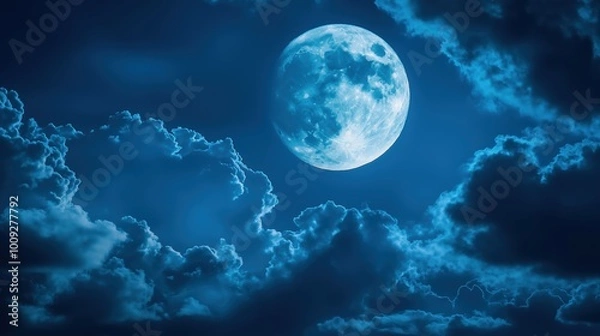 Fototapeta The moon glowing behind the moving clouds