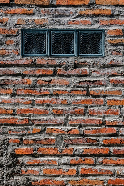 Obraz A textured brick wall with gray mortar and three decorative glass blocks, blending rustic and modern elements, perfect for architectural or background use