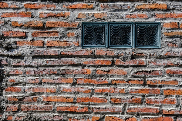 Obraz A textured brick wall with gray mortar and three decorative glass blocks, blending rustic and modern elements, perfect for architectural or background use