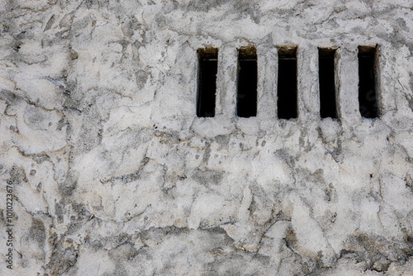 Obraz Close-up of a textured stone wall with vertical slits, creating a unique architectural detail that combines rustic and minimalist elements, perfect for backgrounds or design use