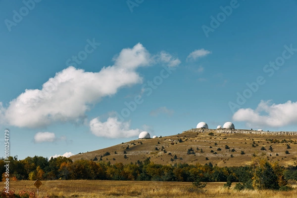Fototapeta Scenic Landscape with Three White Domes on Hilltop Surrounded by Trees in Grassy Field