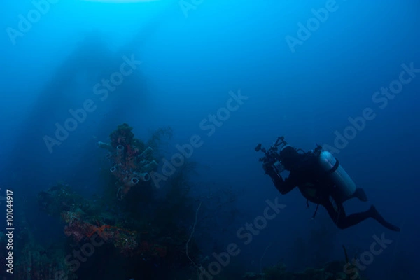 Fototapeta Underwater photographer exploring wreck ship in the deep.